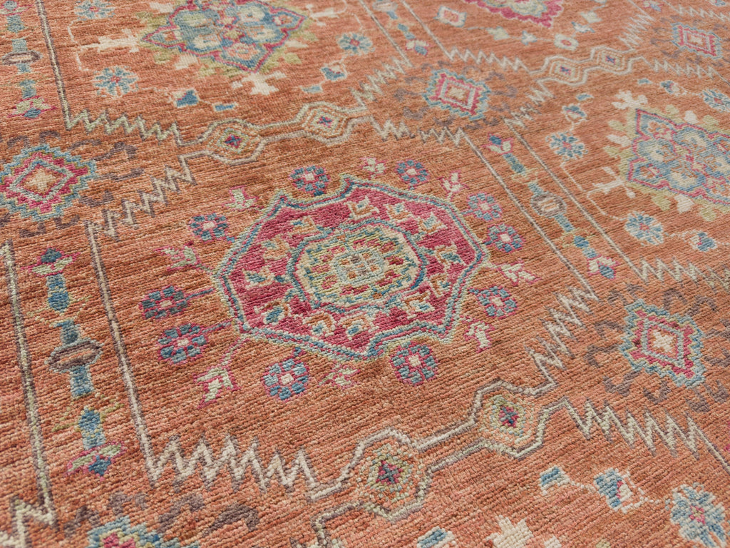 Persian dragonfruit rug with sage green, orange clay, and blue.