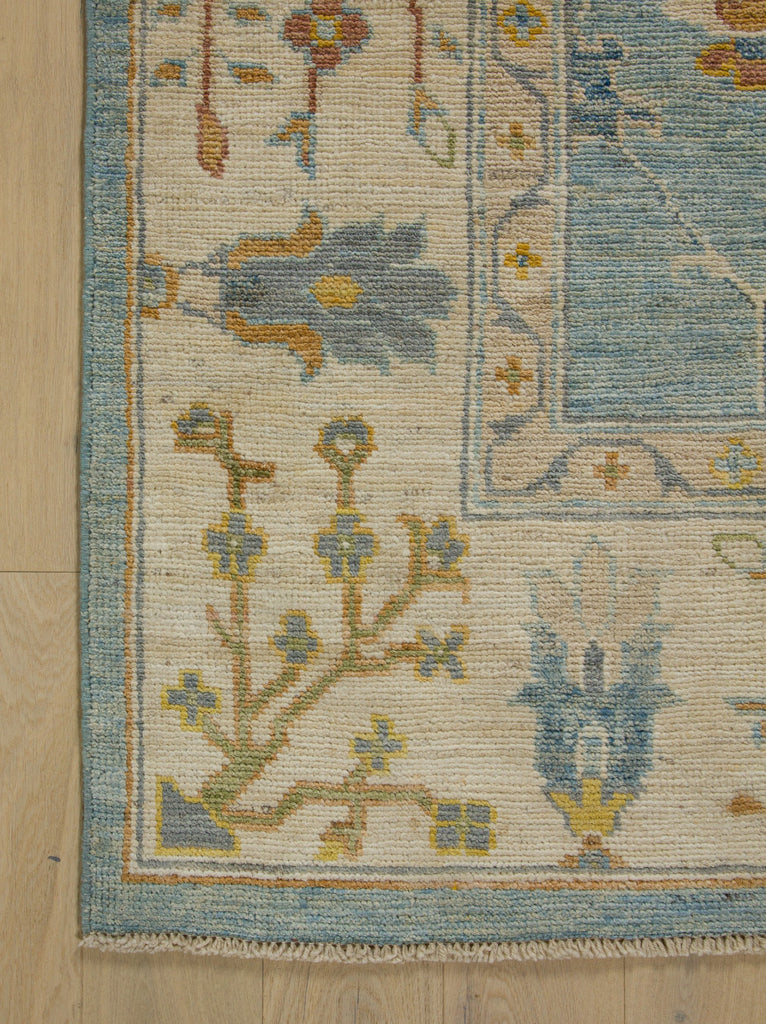 Light blue Oushak rug with dirty gold, sage green and periwinkle grey.
