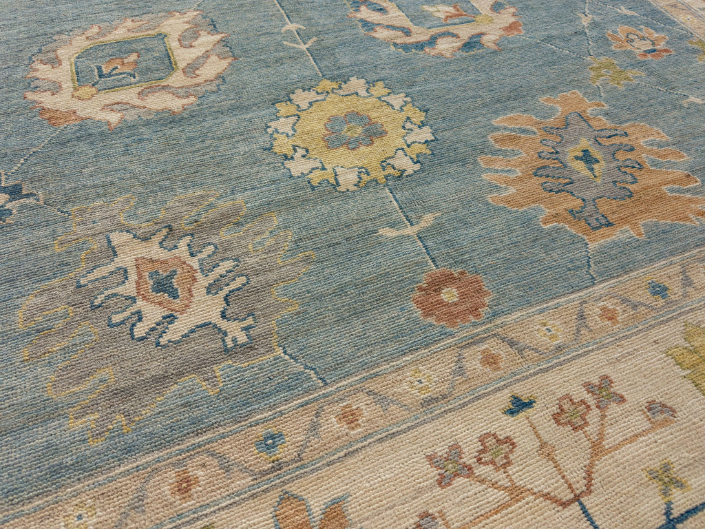 9x12 blue Oushak rug with grey, brown, clay orange, light gold and flowers.