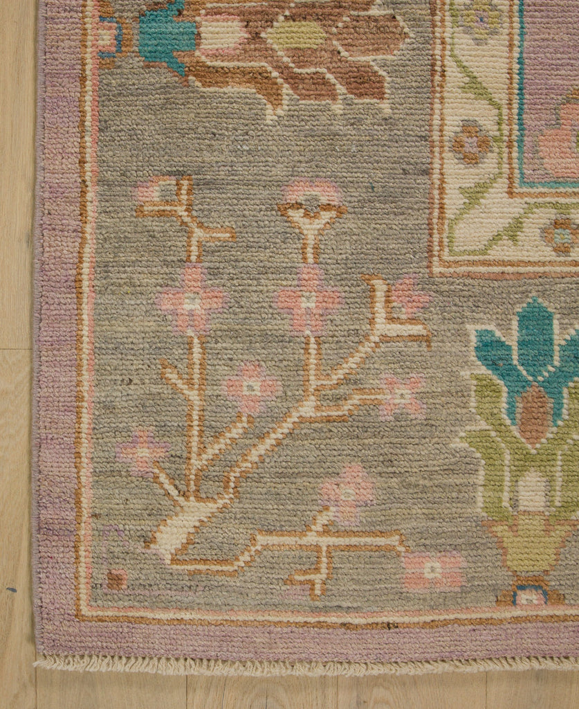 Hand knotted colorful oushak rug in lilac, bright turquoise, clay, and bright green.