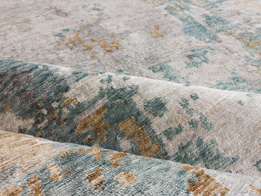 Handmade bamboo silk rug with champagne gold, teal, ivory white and grey colors in a modern design and opulent appearance.