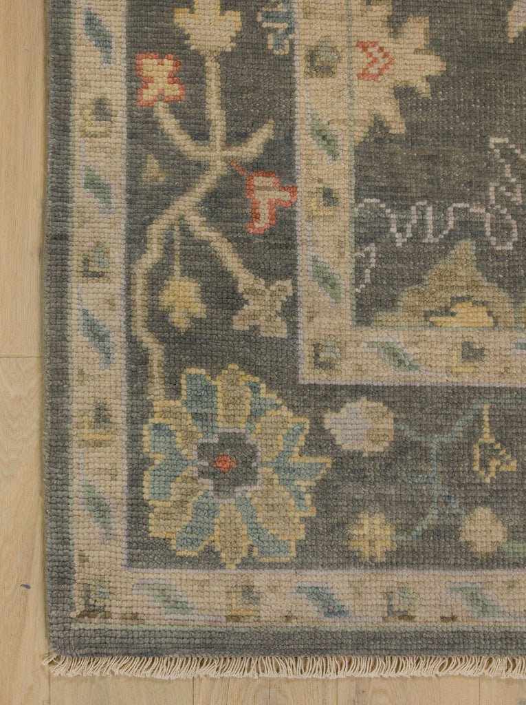 Traditional grey area rug hand knotted of wool with accents of beige, blue, green and light purple lilac.