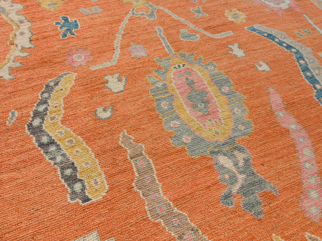 Hand knotted bright Oushak rug in orange with pink and gold in 8 x 10 size.