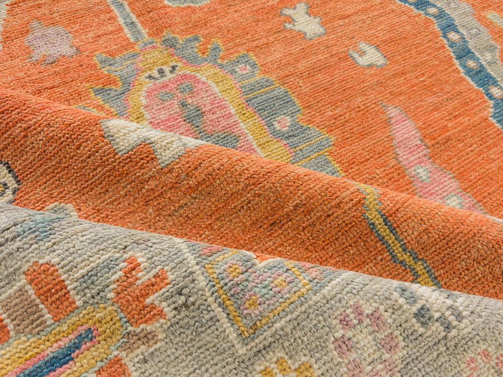 Bright orange Oushak rug made of hand knotted soft wool with accent blue, gold, pink and brown.