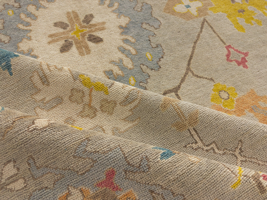 Multi size hand knotted oriental wool rug in warm grey green background and bright periwinkle, indigo, brown bright yellow gold, orange and red.
