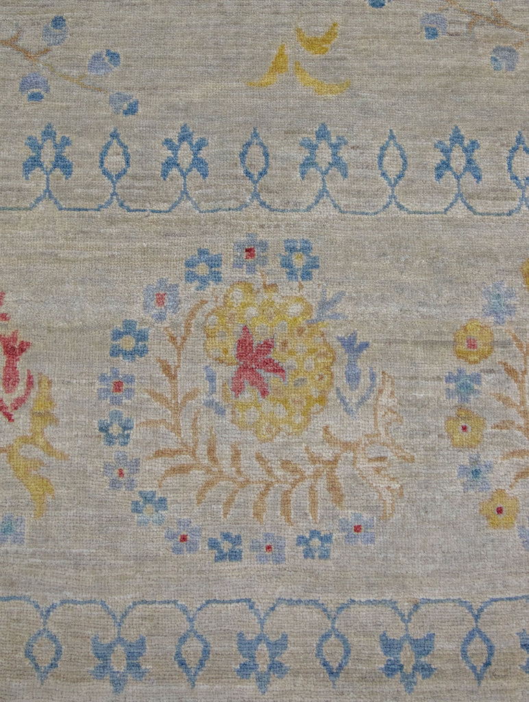 Hand knotted 8x10 wool area rug with floral suzani rug design and grey/beige background and colorful turquoise, teal, blue, bright yellow/gold, and coral red accent colors.