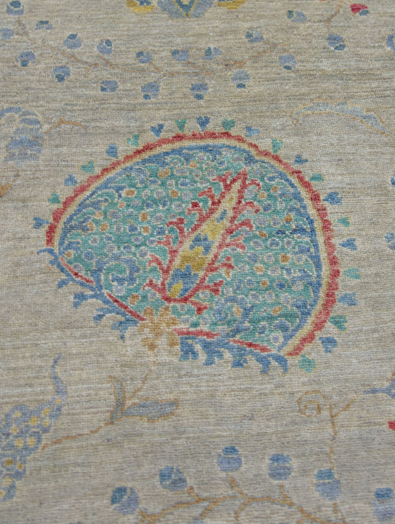 Hand knotted 8x10 wool area rug with floral suzani rug design and grey/beige background and colorful turquoise, teal, blue, bright yellow/gold, and coral red accent colors.