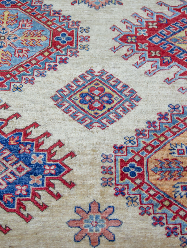 9' x 12' oriental wool rug with geometric southwest design in ivory and red primary color and accent jade green, yellow/gold, navy blue, and light blue accents.