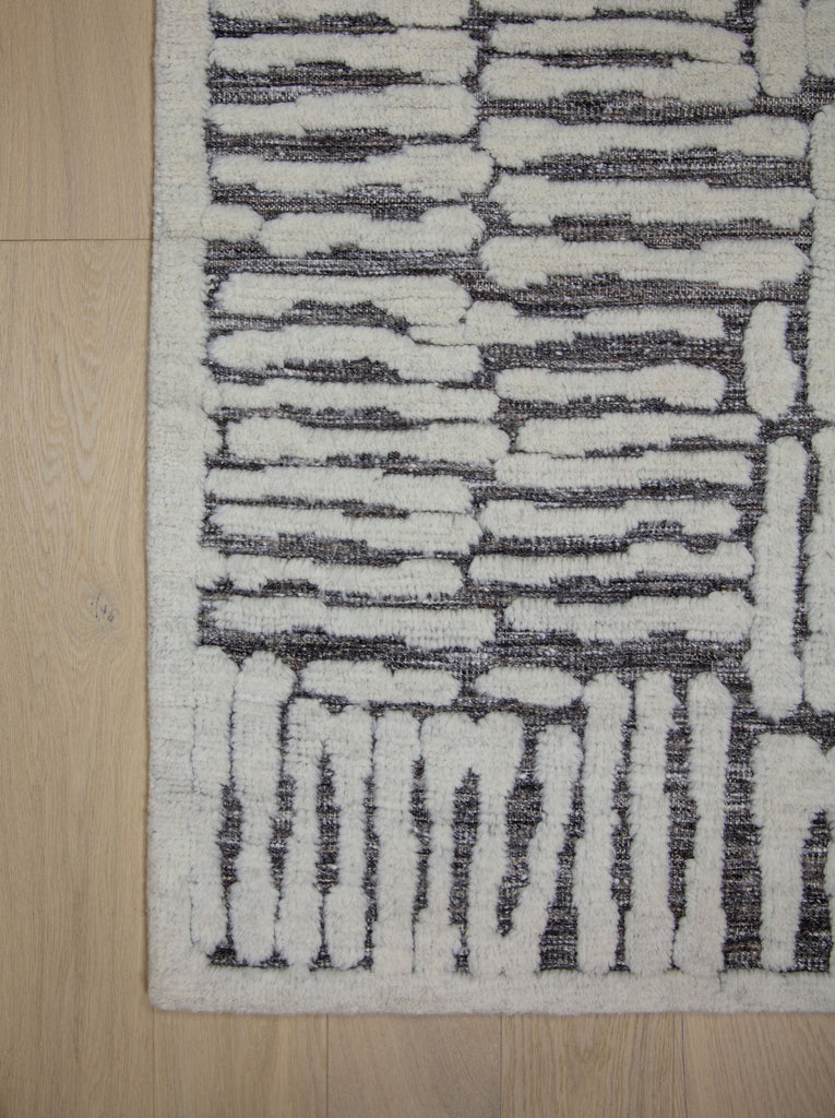 Hand Knotted of wool on a cotton foundation the sahara collection offers a tribal rug with texture, depth and sustainable rug. Colors are ivory white black dark brown and organic. sizes available in 6x9 8x10 9x12 10x14 12x15. performance and durable luxury roya rug.