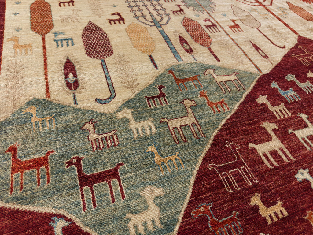 Roya Rugs Hickory North Carolina 9x12 handmade modern red tribal wool rug with ivory, green, beige, light blue and orange with animals, goats, sheep, and mountain hills.