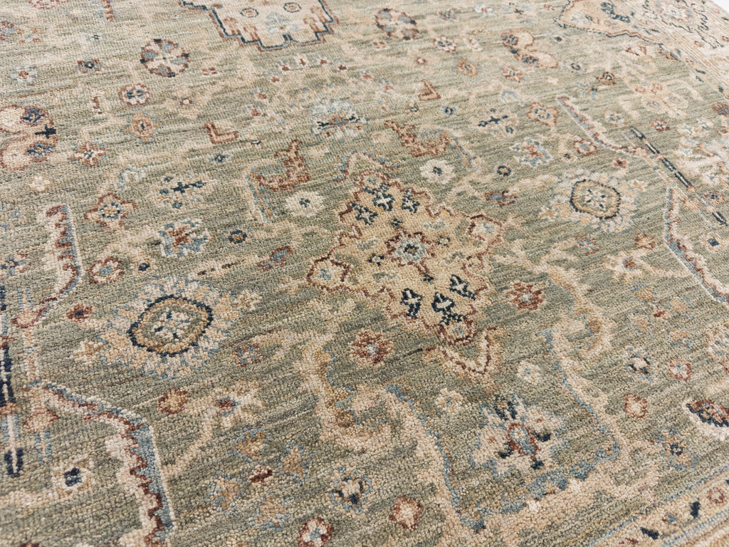 Green floral oriental rug with tan, navy and light blue accents.