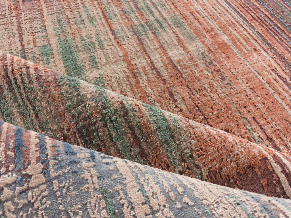 Folded wool and silk rug with green, burgundy red, light and dark blue and beige.